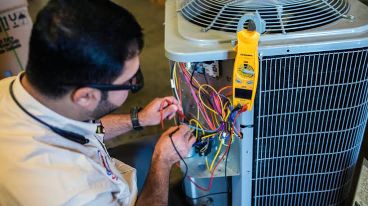 Technician diagnosing the electrical components of an air conditioner