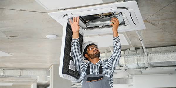 Technician working on a ceiling-mounted HVAC cassette unit