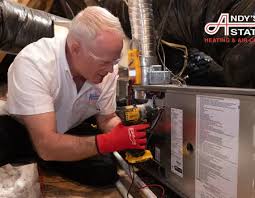 Technician servicing a furnace beneath connected ductwork
